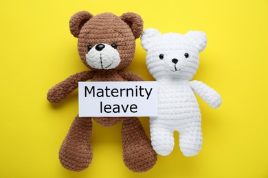 Photo of Toy bears and note with text Maternity Leave on yellow background, flat lay