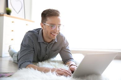 Photo of Young blogger with laptop on floor at home