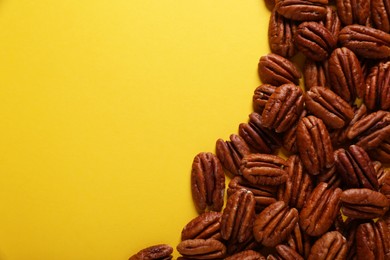 Photo of Tasty pecan nuts on yellow background, flat lay. Space for text