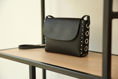 Photo of Stylish woman's bag on shelf in boutique