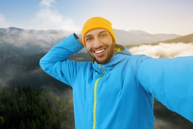 Image of Smiling young man taking selfie in mountains