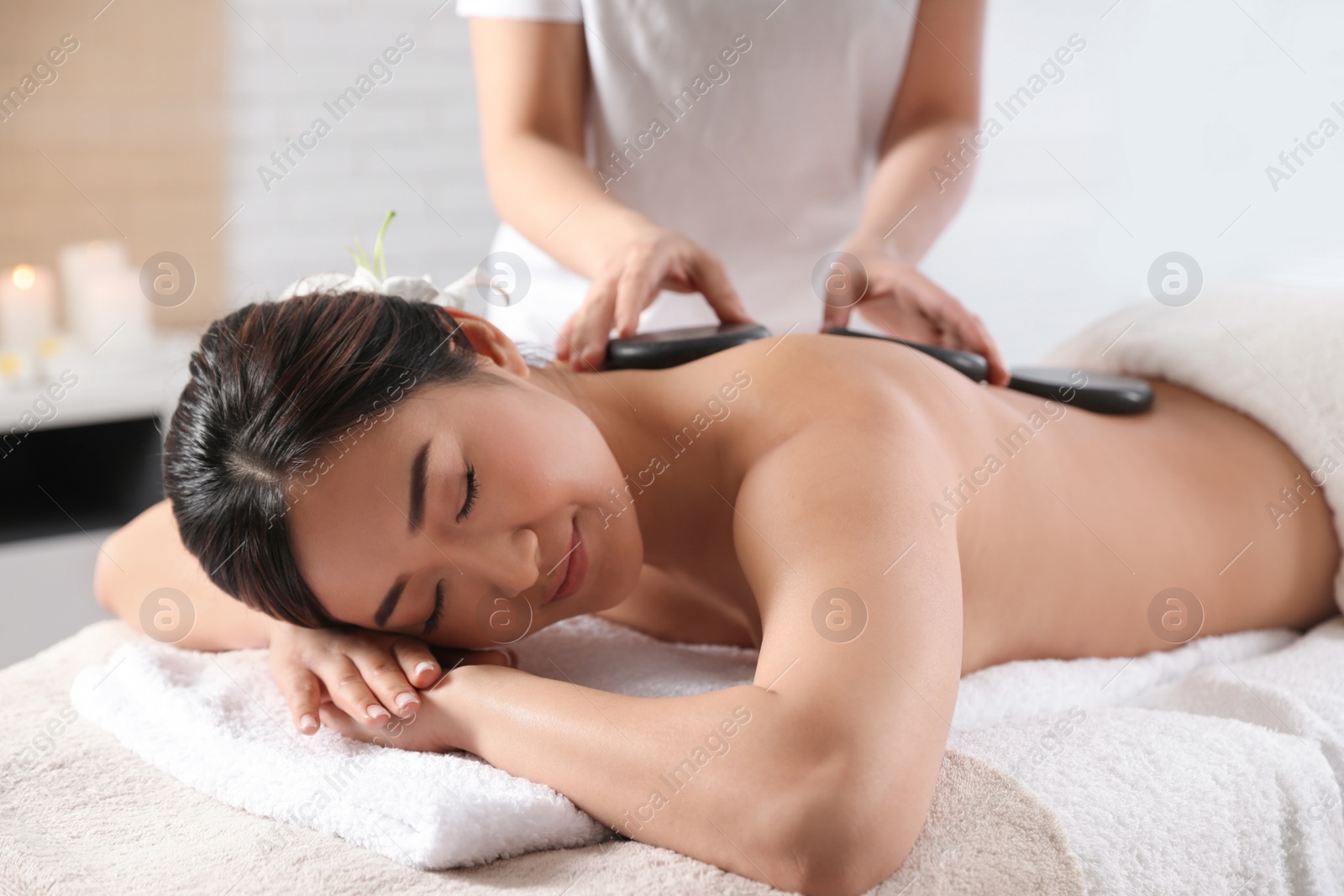 Photo of Beautiful Asian woman getting hot stone massage in spa salon