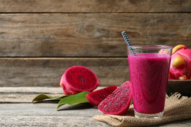 Photo of Glass of tasty pitahaya smoothie and fresh fruits on wooden table, space for text