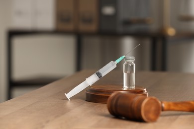 Photo of Law concept. Gavel, syringe and glass vial on wooden table, space for text