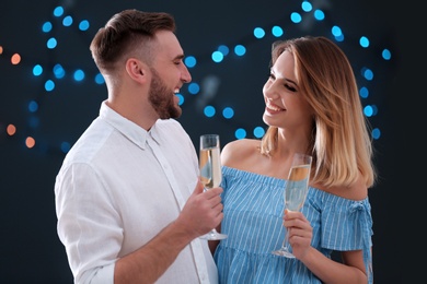 Photo of Happy couple with champagne in glasses on blurred background