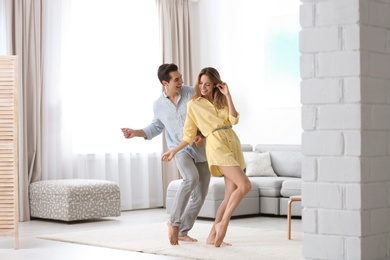Photo of Beautiful young couple dancing in living at home
