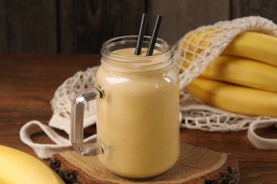Photo of Mason jar with banana smoothie on wooden table