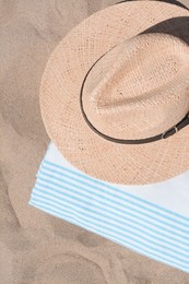 Photo of Straw hat and beach towel on sand, top view