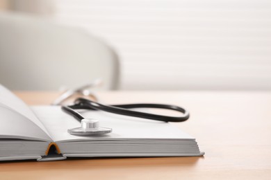 Photo of Book and stethoscope on wooden table indoors, space for text. Doctor education