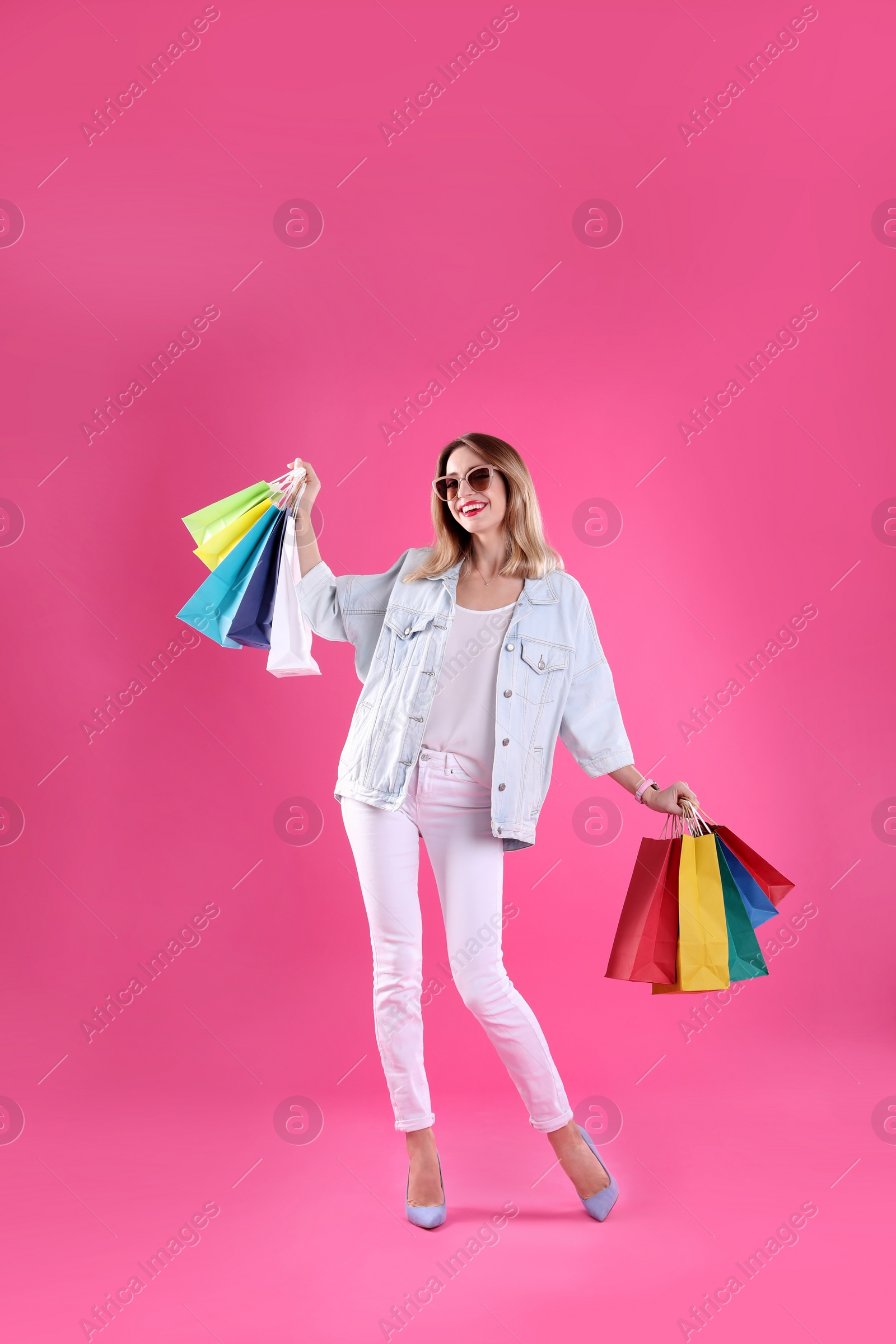 Photo of Beautiful young woman with shopping bags on color background