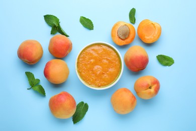 Photo of Apricot puree in bowl and fresh fruits with mint on light blue background, flat lay