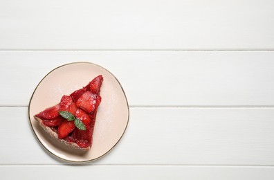 Photo of Piece of delicious strawberry tart with mint on white wooden table, top view. Space for text