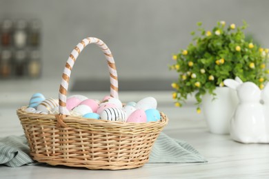 Photo of Easter basket with many painted eggs on white marble table