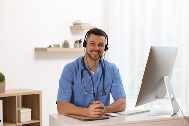 Doctor with headset sitting at desk in clinic. Health service hotline