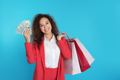 African-American businesswoman with money and shopping bags on color background. Space for text