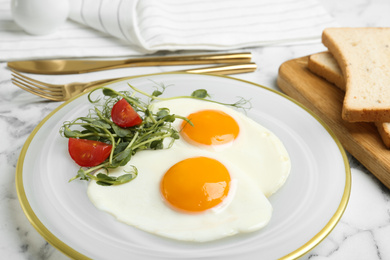 Photo of Tasty fried eggs with tomato and sprouts on white marble table, closeup