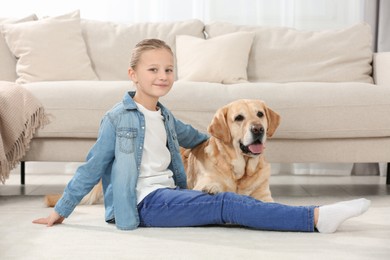 Photo of Cute child with her Labrador Retriever on floor at home. Adorable pet