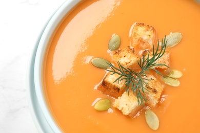 Photo of Tasty creamy pumpkin soup with croutons, seeds and dill in bowl on white background, closeup