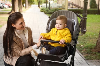 Photo of Happy mother with her son in stroller outdoors