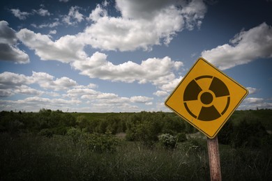 Image of Radioactive pollution. Yellow warning sign with hazard symbol near contaminated area outdoors. Space for text