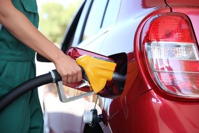 Photo of Young worker refueling car at modern gas station, closeup