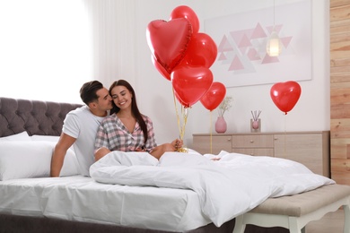 Photo of Beautiful couple with heart shaped balloons in bedroom