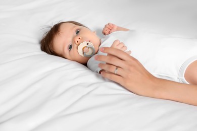 Photo of Mother holding hand of her little baby on bed, closeup