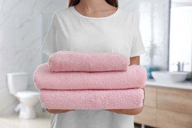 Photo of Woman holding fresh towels in bathroom, closeup