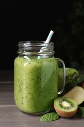 Photo of Delicious kiwi smoothie and ingredients on wooden table