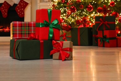 Photo of Many gift boxes near decorated Christmas tree and fireplace indoors