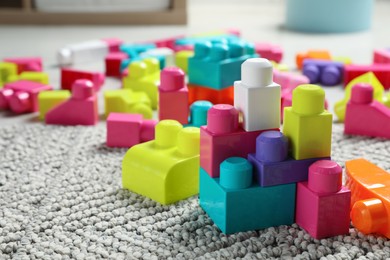Photo of Colorful plastic building blocks on floor indoors, space for text