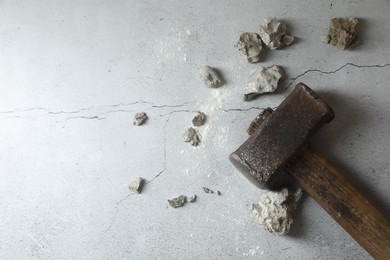 Photo of One sledgehammer and broken stones on grey textured background, flat lay. Space for text