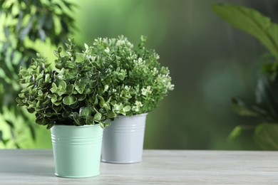 Photo of Aromatic oregano and thyme growing in pots on white wooden table outdoors, space for text
