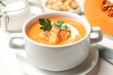 Photo of Delicious pumpkin soup served on white table