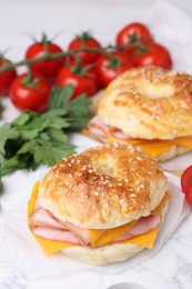 Photo of Delicious bagels with ham and cheese on white table