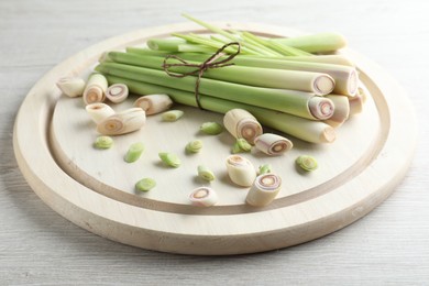 Whole and cut fresh lemongrass on white wooden table