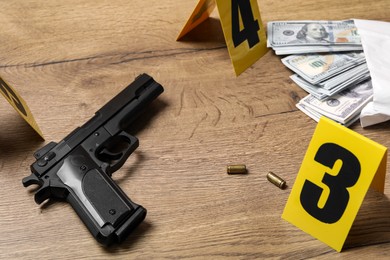 Photo of Gun, money and shell casings on wooden background. Crime scene