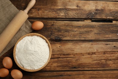 Photo of Flat lay composition with wheat flour and eggs on wooden table. Space for text