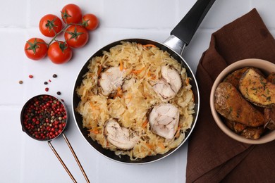 Photo of Frying pan with sauerkraut, chicken and products on white tiled table, flat lay