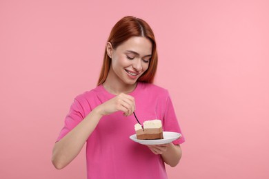 Photo of Young woman eating piece of tasty cake on pink background