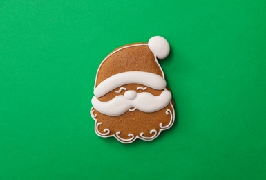 Photo of Christmas Santa Claus face shaped gingerbread cookie on green background, top view