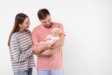 Photo of Happy family. Parents with their cute baby on light background, space for text