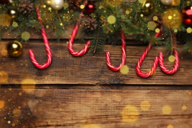 Image of Christmas composition with candy canes and festive decor on wooden table, space for text. Bokeh effect