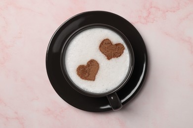 Photo of Cup of aromatic coffee with heart shaped decoration on pink marble table, top view