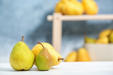 Photo of Fresh ripe pears on light table against blurred background. Space for text