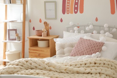 Photo of Comfortable bed with pillows and plaid in child's room. Interior design