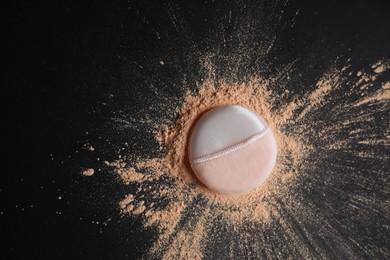 Puff applicator and loose face powder on black background, flat lay