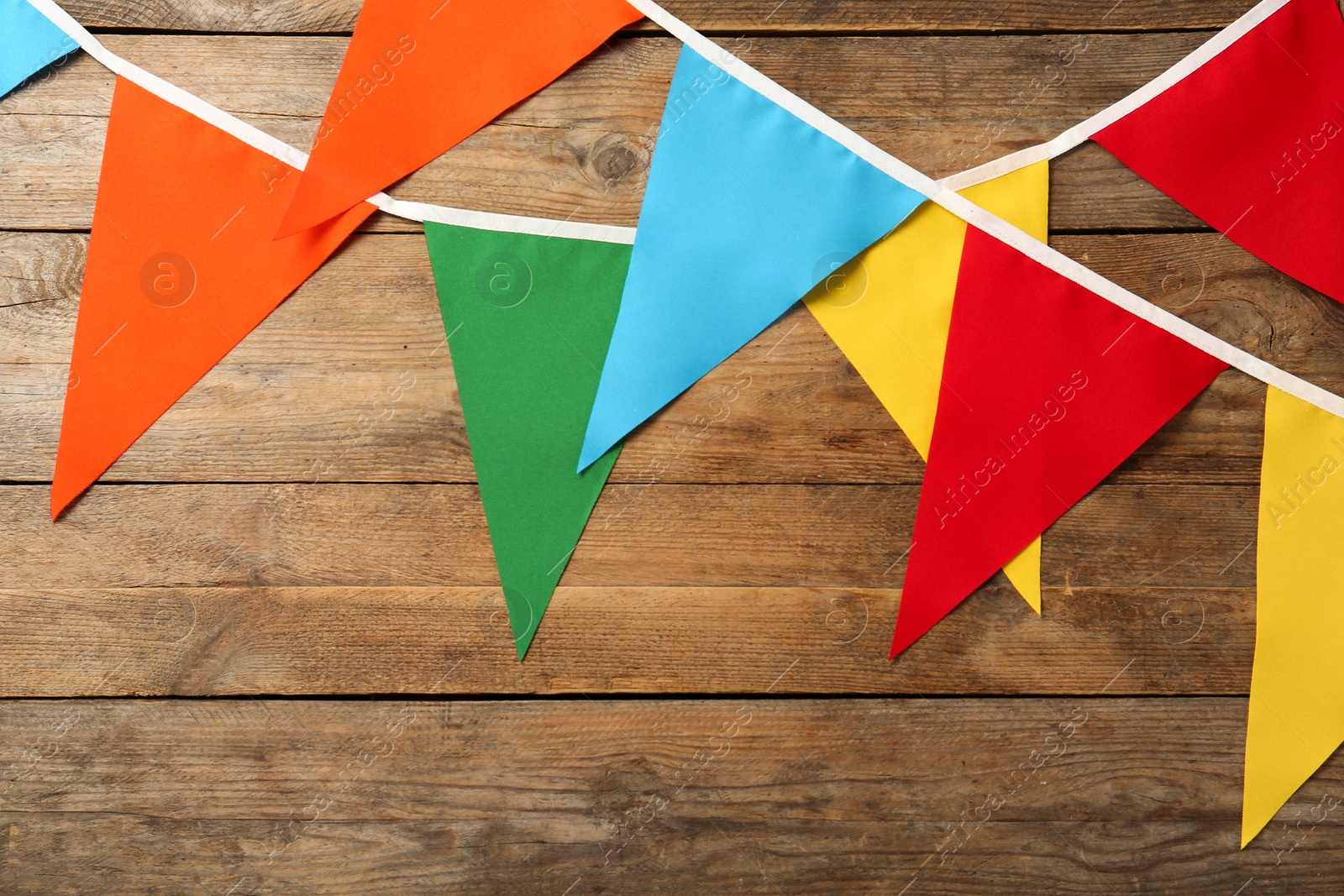 Photo of Buntings with colorful triangular flags on wooden background. Festive decor