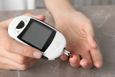 Photo of Woman checking blood sugar level with glucometer at table. Diabetes test