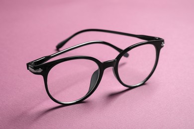 Stylish pair of glasses with black frame on pink background